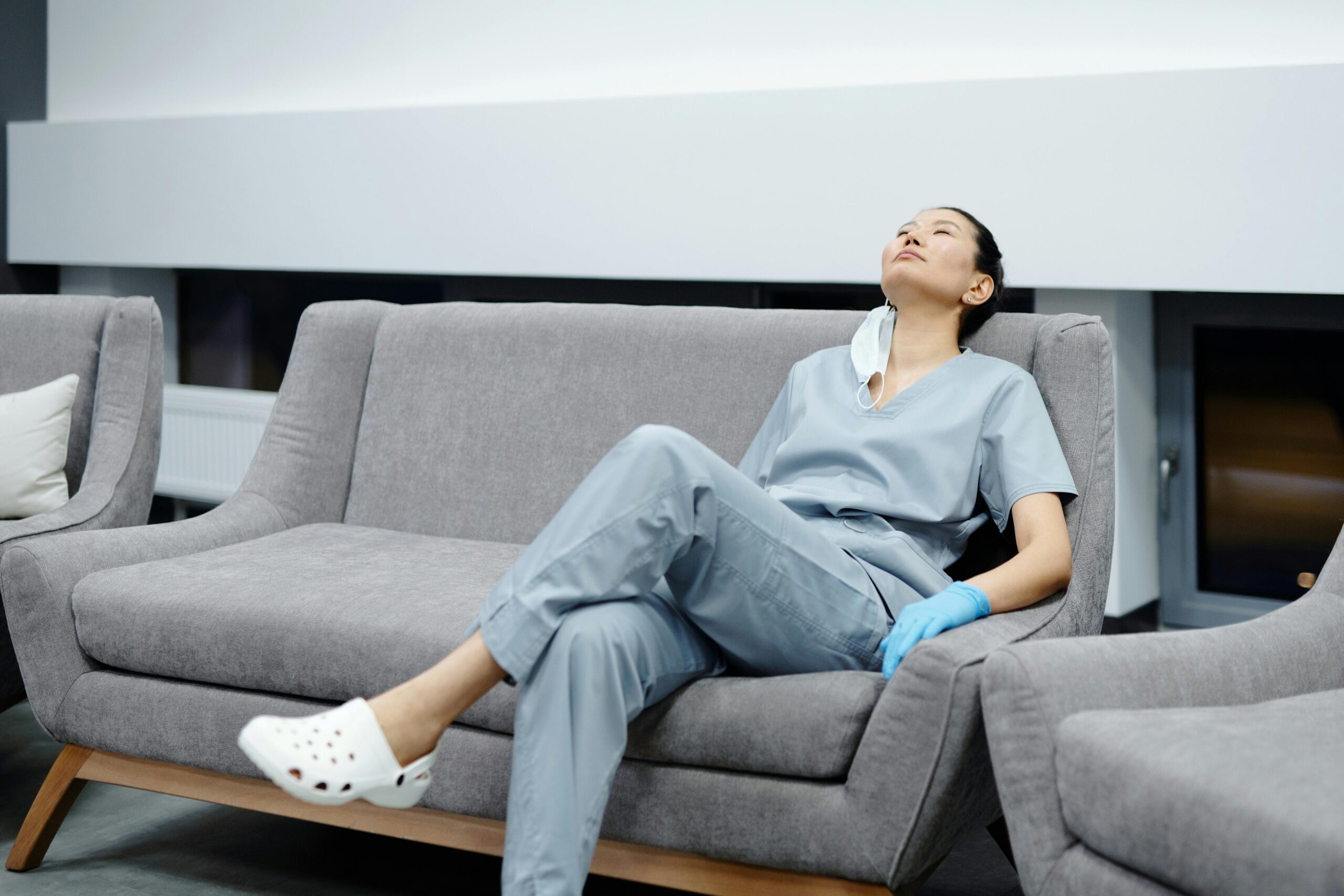 Jeune femme médecin fatiguée qui regarde en l'air assise sur un canapé