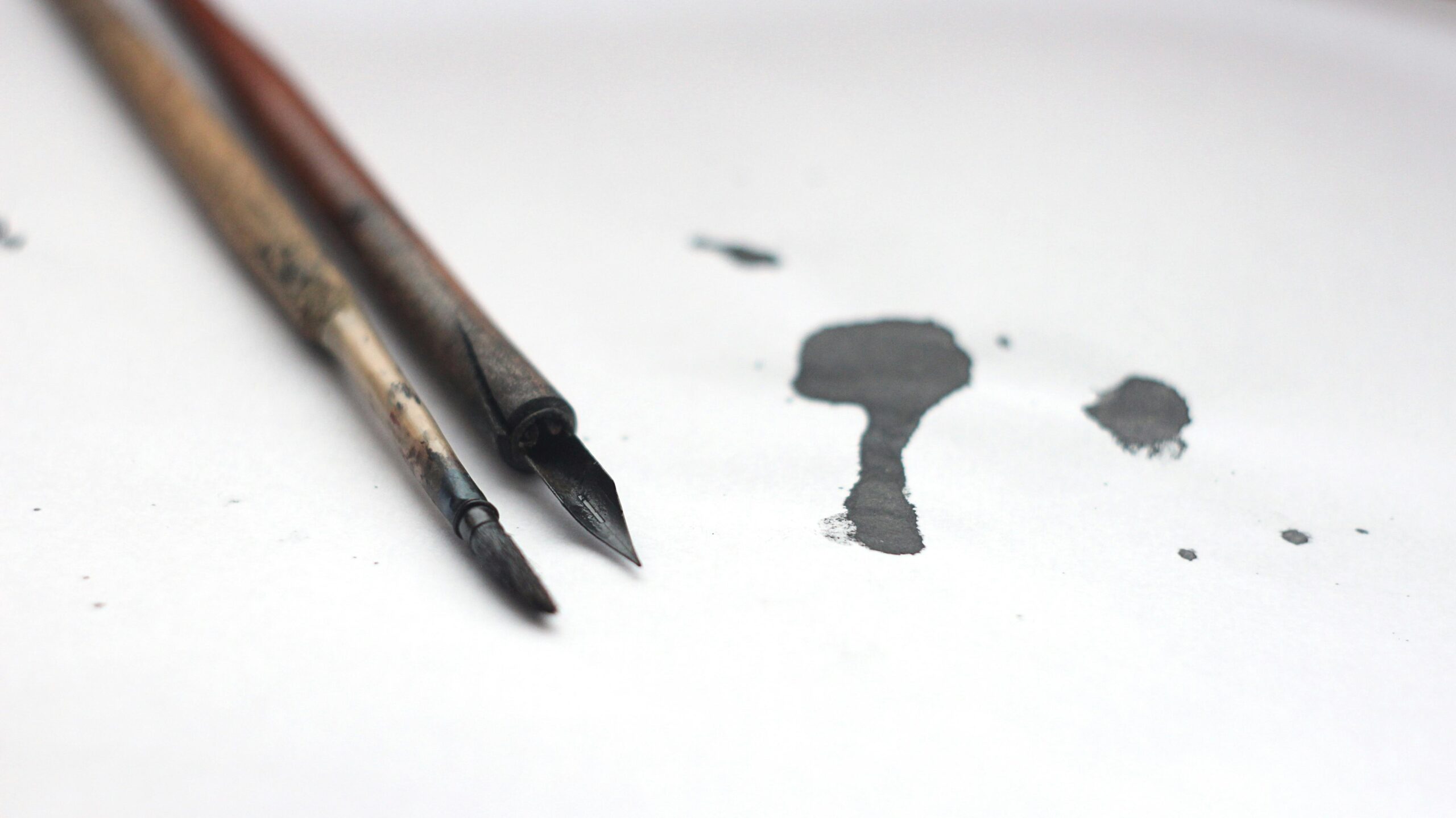 Tache d'encre à côté d'une plume et d'un encrier, illustration métaphorique du métier de coach qui transforme la matière brute en écriture