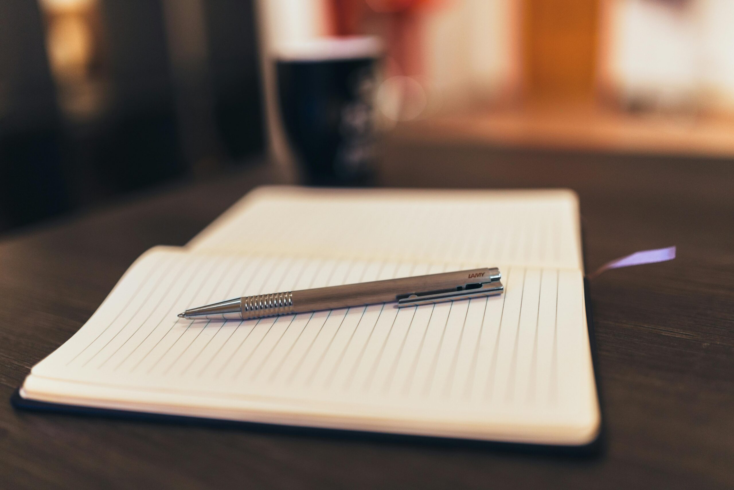 Carnet de notes ouvert posé sur une table, à côté d'une tasse de café et d'un livre, illustration de l'idée d'apprendre du quotidien sans cadre formel