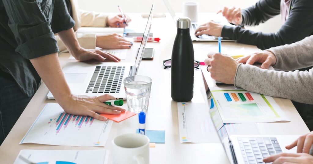 Collaborateurs réunis autour d'une table de travail, échangeant idées et analyses dans une démarche collective de diagnostic d'entreprise.